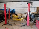 a car that is parked in a garage next to two red lifts