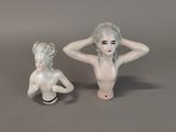two figurines of a woman sitting next to each other