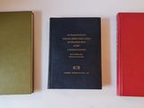 three books are lined up on a table with a white background