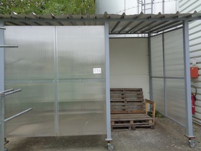 a metal structure with a bench in front of it