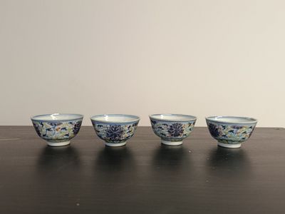 four blue and white bowls sitting on top of a wooden table