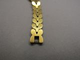 gold tone bracelet with a heart shaped clasp on a black background