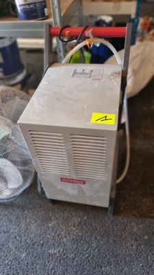 un petit climatiseur posé par terre à côté d'un ventilateur