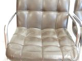 two brown leather chairs sitting next to each other on a white floor