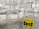 two glass bottles sitting next to each other on a table