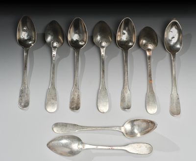 six cuillères et deux cuillères en argent sur une surface blanche