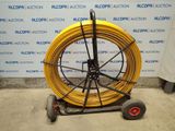a cart with a yellow hose on it in front of a wall