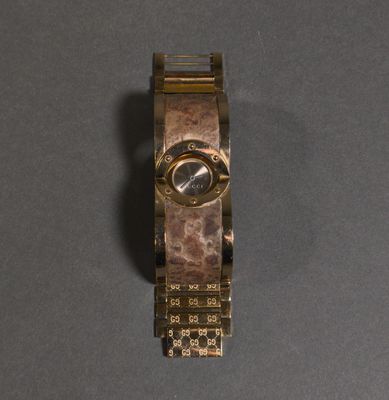 a close up of a gold watch on a gray surface