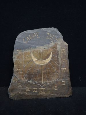 une pierre sur laquelle est gravé un cadran solaire, posée sur une surface noire
