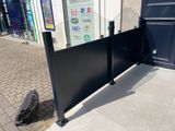 une clôture noire sur le trottoir, à côté d'un immeuble