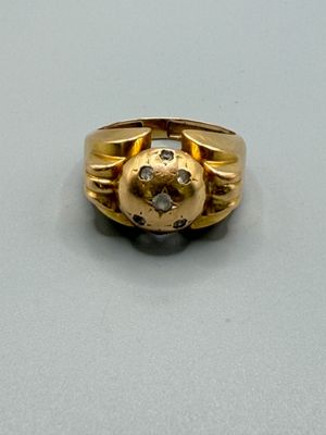 une bague en or sertie d'un diamant, posée sur une table