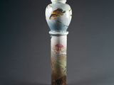 a glass vase with a bird on it on a pedestal