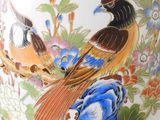 a vase with a bird design on it sitting on a table
