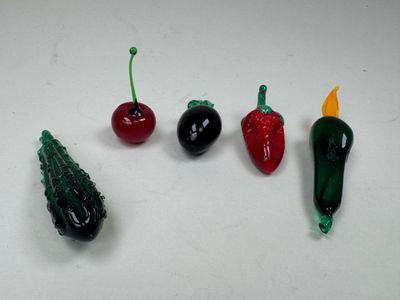 cinq poivrons de couleurs différentes et une cerise sur une surface blanche