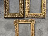 trois cadres dorés posés sur une surface en béton
