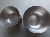 two silver bowls sitting on a table next to each other