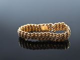 a close up of a gold rope bracelet on a black surface