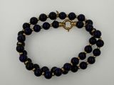 a close up of a blue beaded bracelet on a white surface