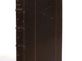 an old brown book sitting on top of a white surface