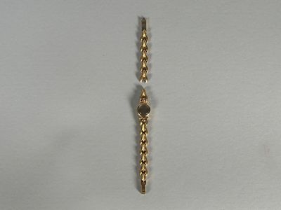 un bracelet en or orné d'une perle, posé sur un fond blanc