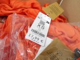 an orange shirt in a box with a price tag on it