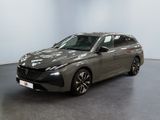 La voiture grise est garée dans une grande pièce au sol noir.