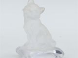 une figurine de chat blanc posée sur un socle transparent