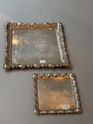 une paire de plateaux plaqués argent posés sur une table sur laquelle se trouve une étiquette