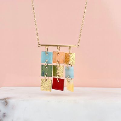 a close up of a necklace on a marble surface with a pink background
