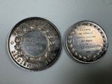two silver coins sitting on top of each other on a table