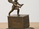 a bronze statue of a cupid holding a tennis racket