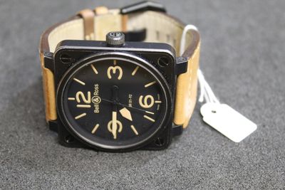 a black and tan watch with a tag on it