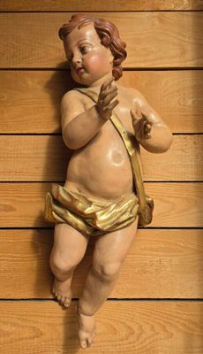 a statue of a baby with a bow on a wall