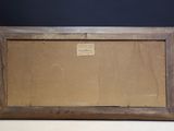 an old picture frame with a label on it sitting on a table