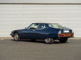 an old blue car parked in front of a garage door