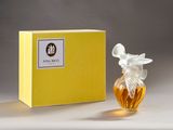 perfume bottle in front of a yellow box on a white surface