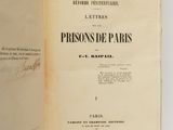 un livre ouvert posé sur une surface blanche, avec un titre écrit à la main