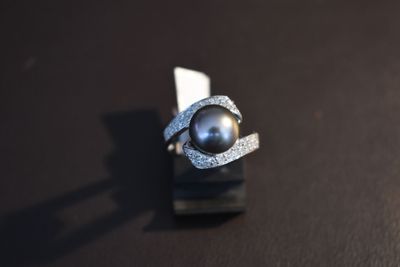 a ring with a black pearl on it on a black surface