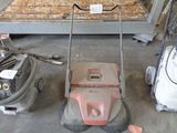 a lawn mower sitting on the floor next to other items