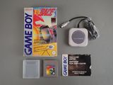 une Game Boy à côté d'une boîte de jeu et d'un chargeur