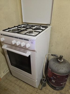 un poêle blanc et un bidon de gaz dans un coin de la pièce