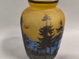 a yellow vase with a picture of a forest on it