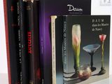 three books on a white table with a vase and a vase on it