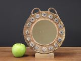 a green apple sitting next to a mirror on a wooden table