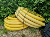 a pile of yellow hoses sitting next to a trash can