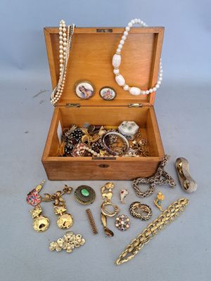 a wooden box filled with assorted jewelry on a table