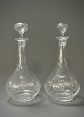 une paire de carafes en verre transparent posées sur une table devant un fond gris
