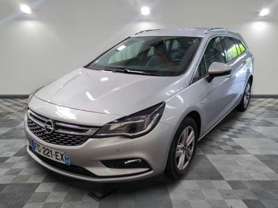 L'Opel argentée est garée dans une grande pièce au sol carrelé en damier.