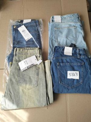 trois paires de jeans posées sur une boîte en carton