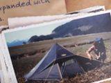 une carte postale sur laquelle figure la photo d'un homme en train de monter une tente